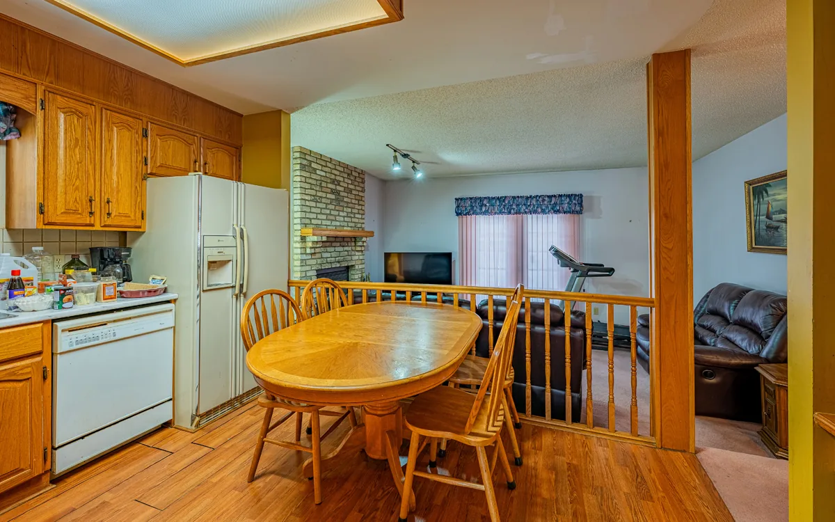 Before — a dated kitchen with oak cabinets, a dropped ceiling light and a spindle railing closing off the living room