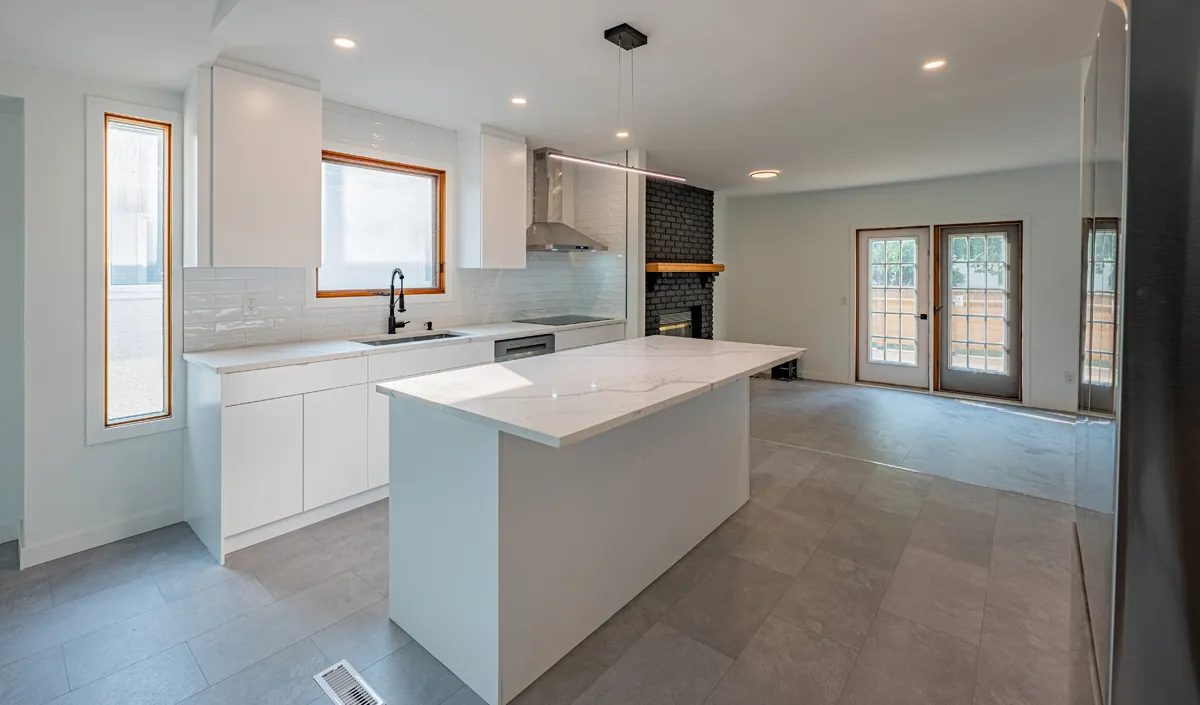 A finished PHS kitchen in Winnipeg — white cabinetry, island and a brick feature wall